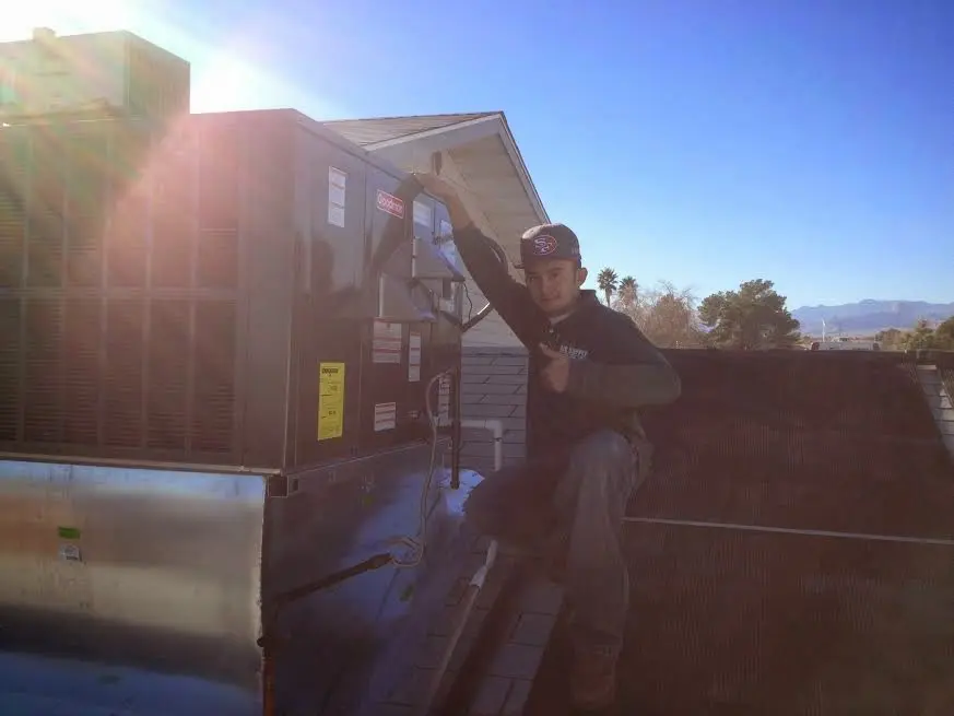 HVAC technician performing AC Tune-Up on a rooftop unit in Mansfield